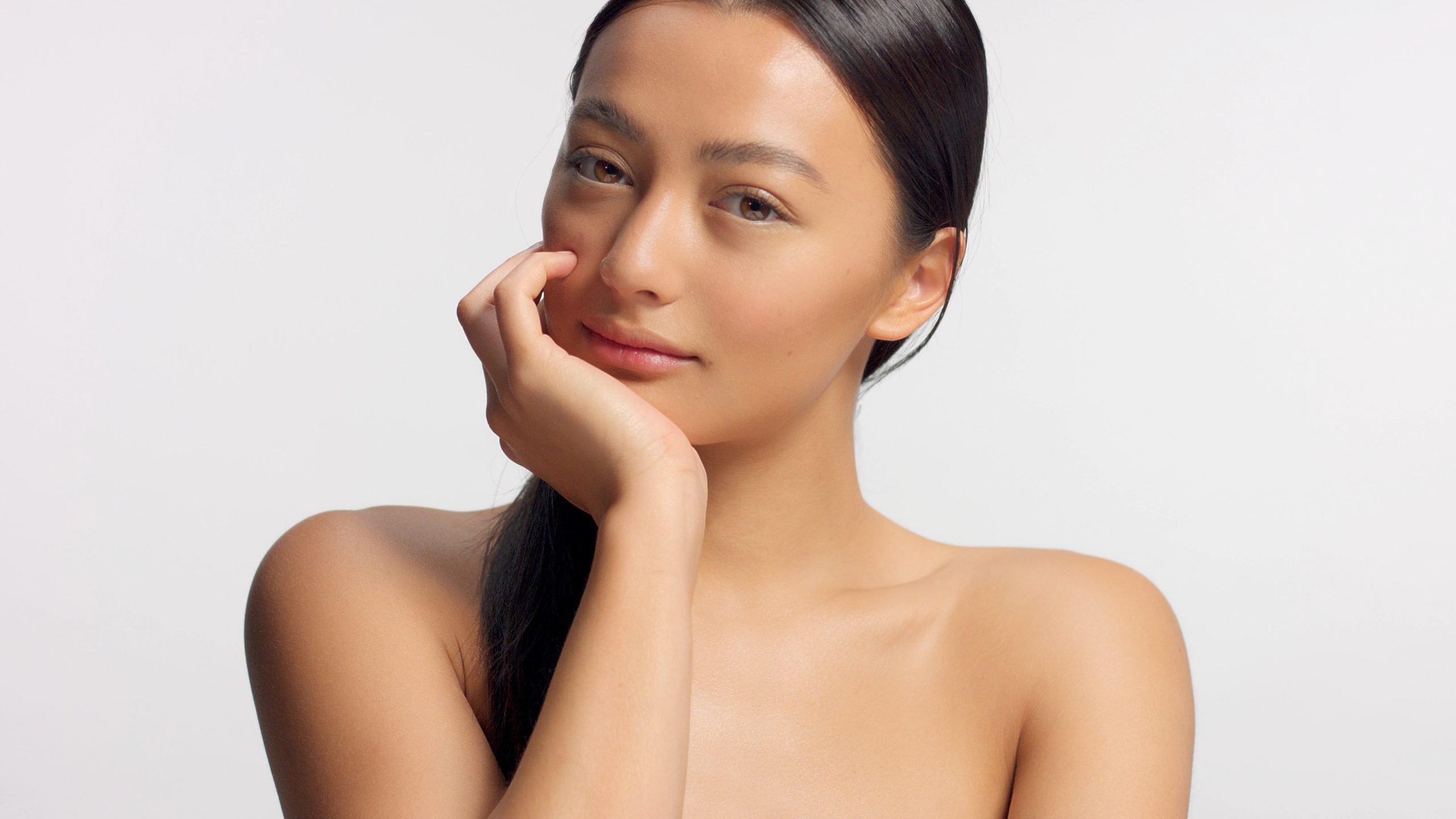 mixed race model with head rest on hand watching to the camera. Ideal glowy skin, head and shoulders crop